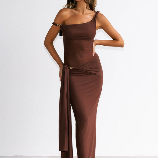 Woman wearing a brown one-shoulder dress against a white background