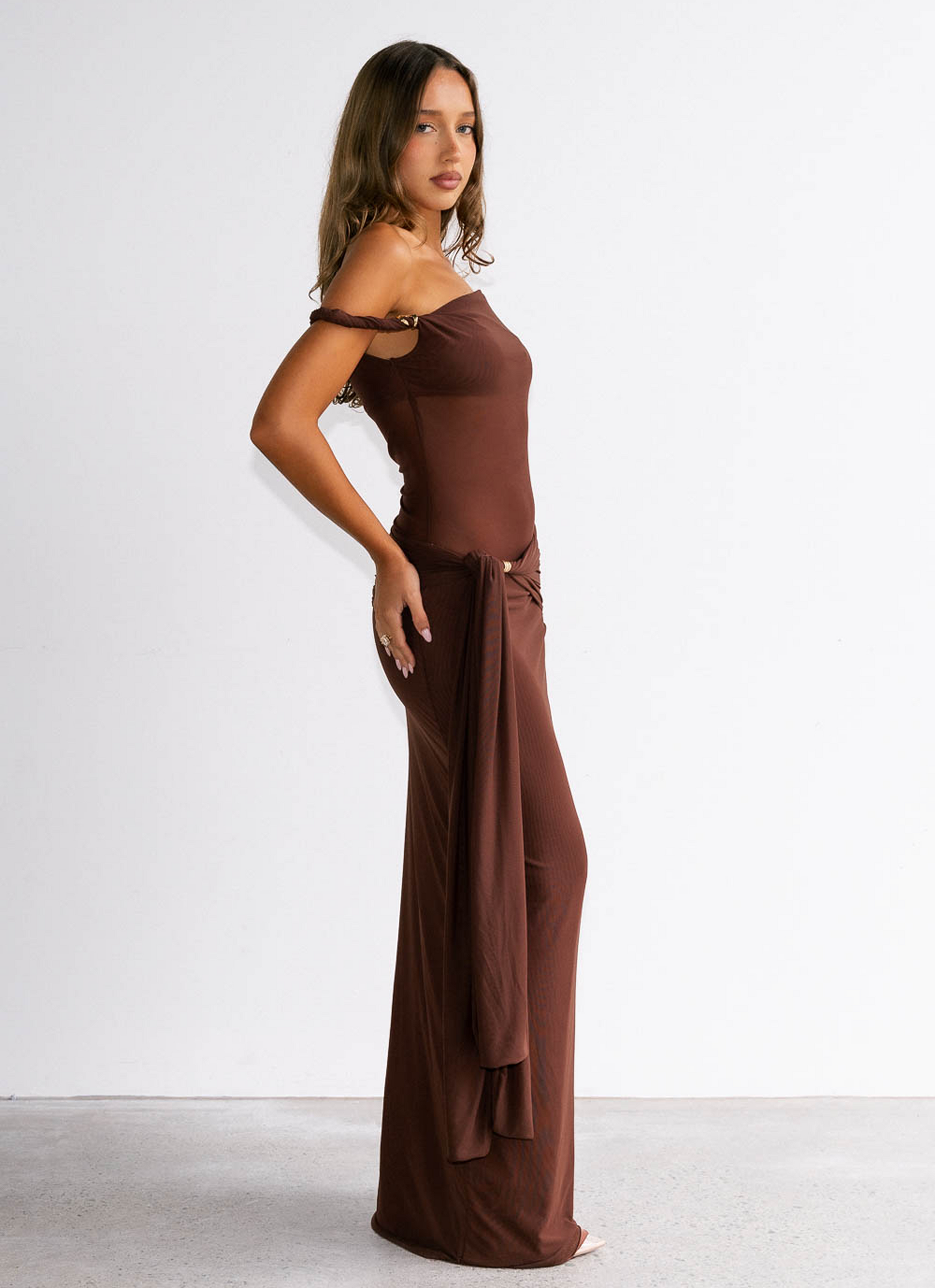 Woman wearing a brown off-shoulder dress against a white background