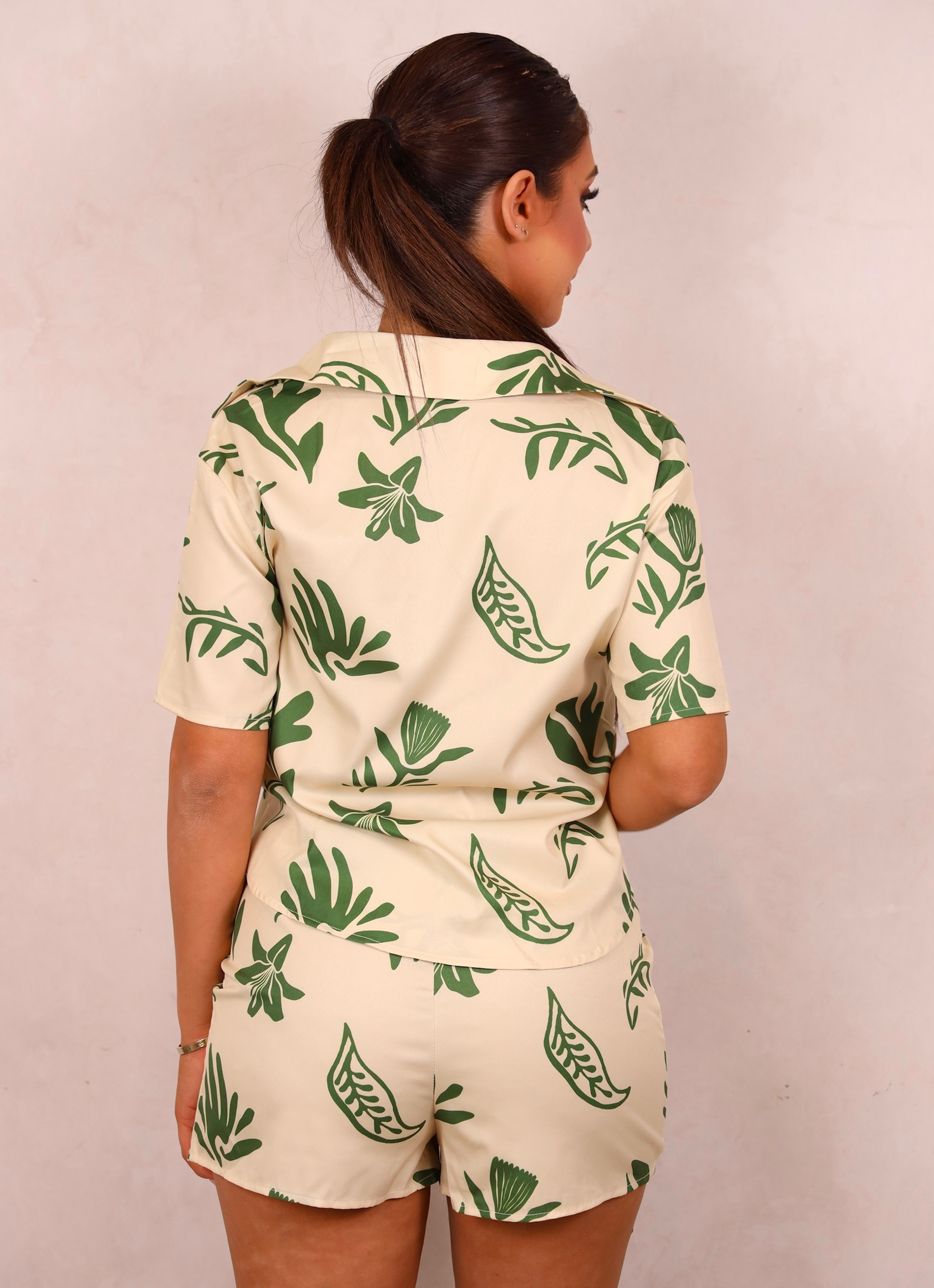Person wearing a green and white leaf-patterned outfit against a plain background
