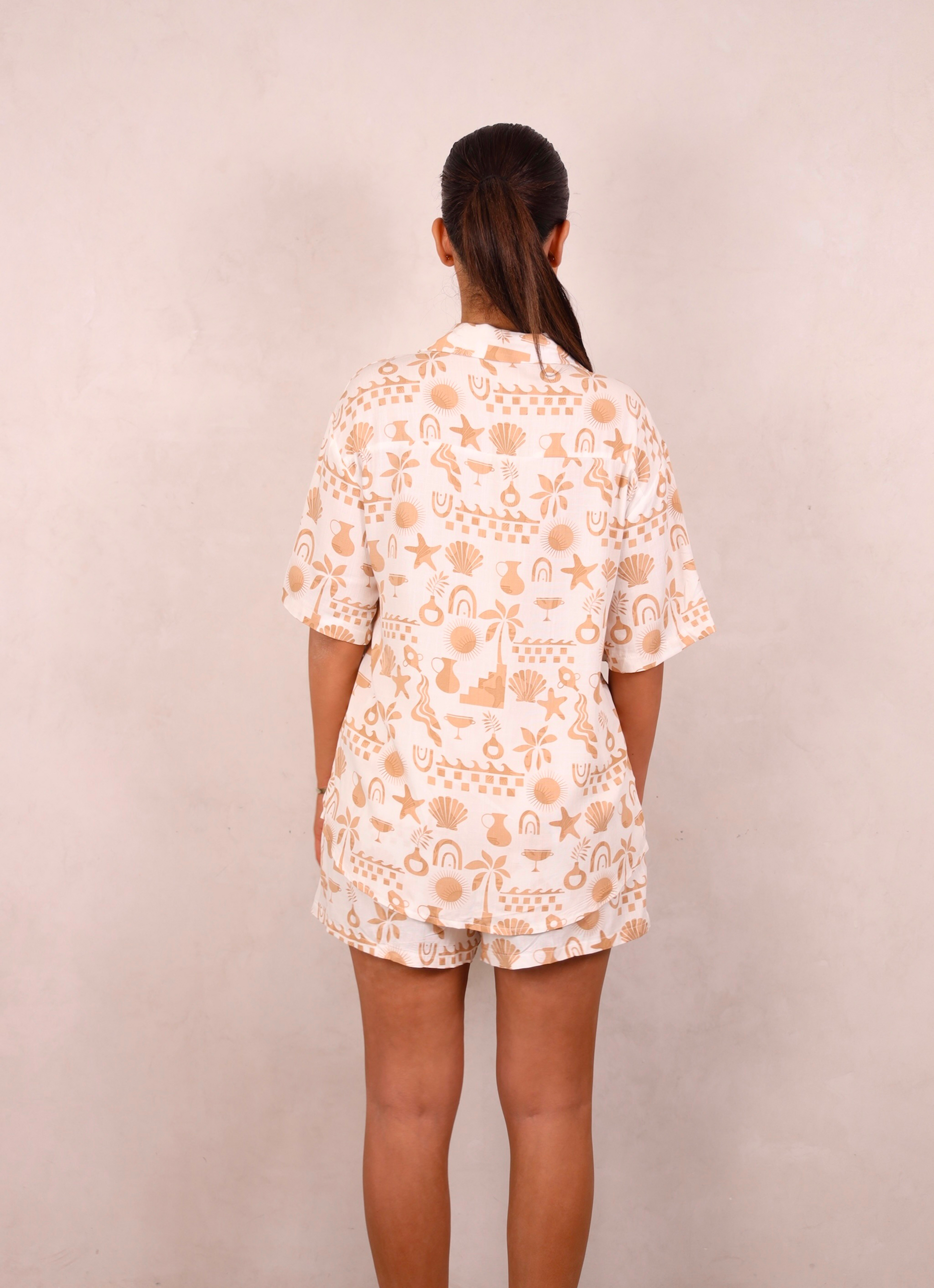 Person wearing a white outfit with peach floral pattern against a beige background