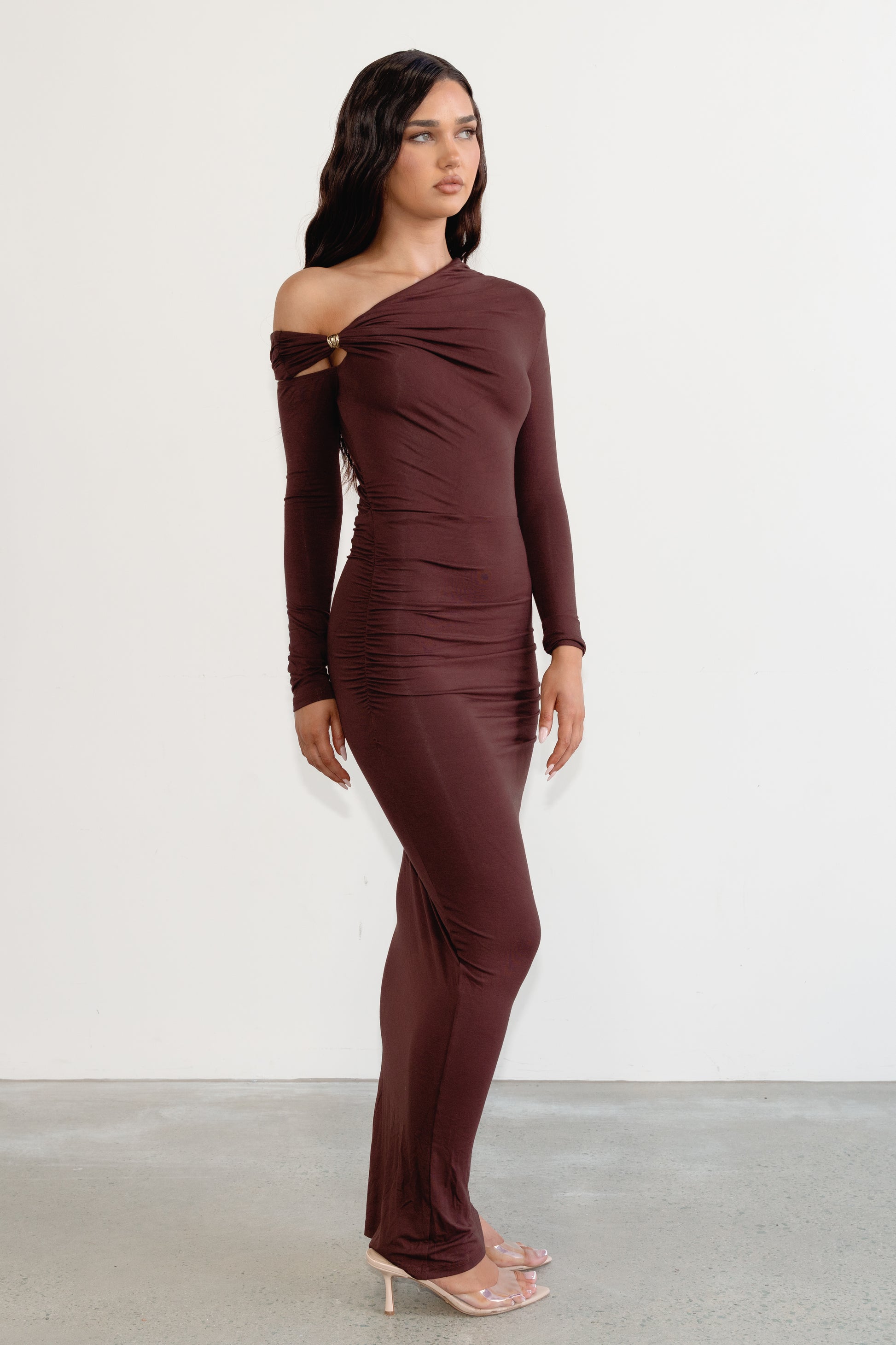 Woman wearing a brown off-shoulder dress against a white background