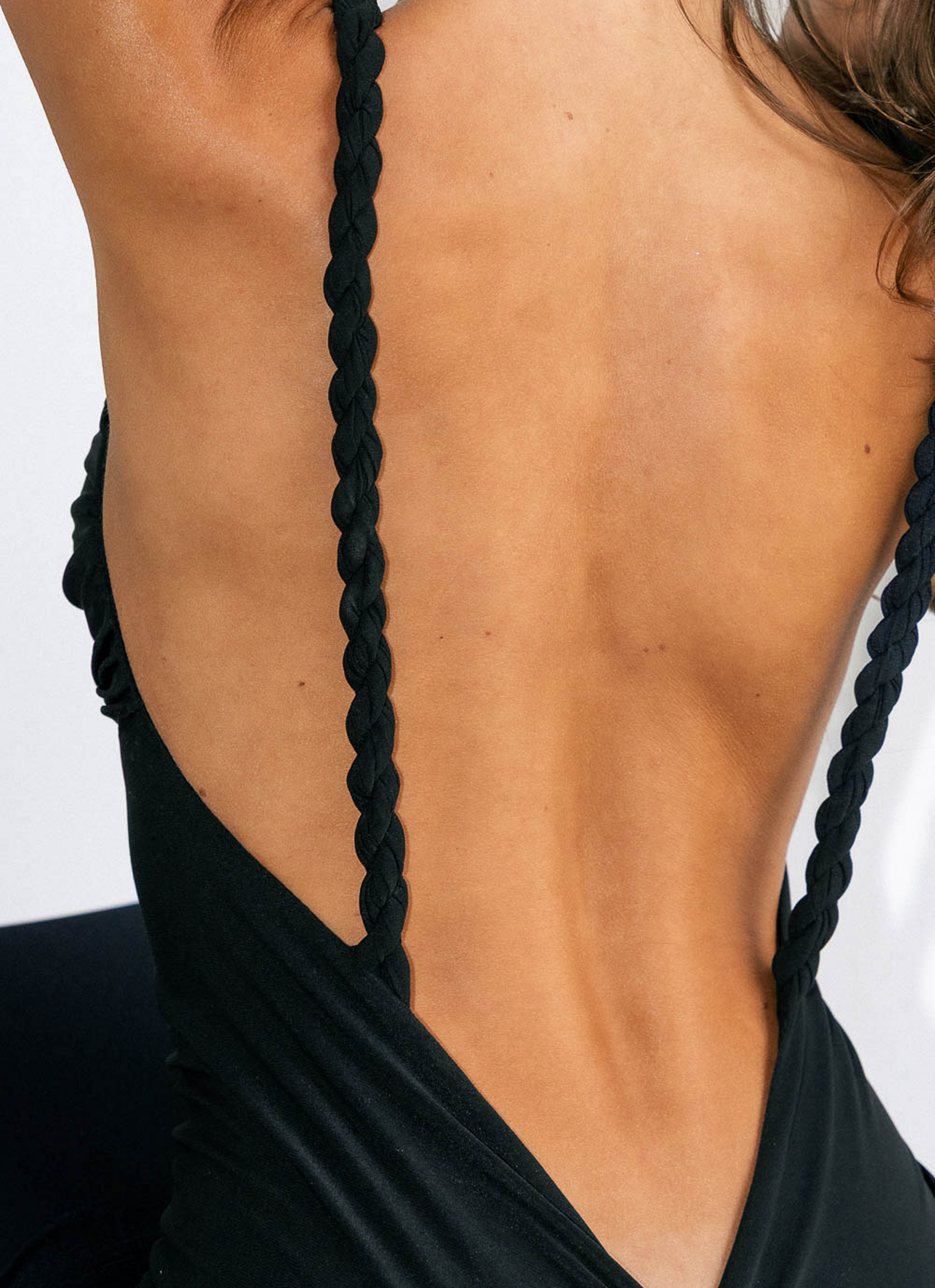 Black dress with braided straps on a plain background