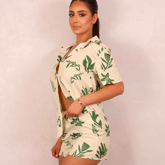 Woman wearing a tropical print outfit against a plain background