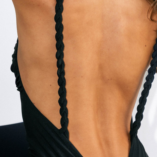 Black dress with braided straps on a plain background